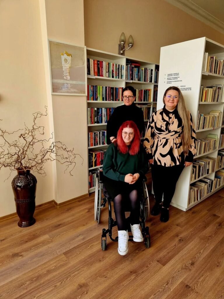 Trys moterys bibliotekos patalpose